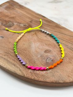 a wooden board with a colorful bracelet on it's end and a yellow string attached to it