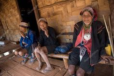 three women sitting on a wooden bench in front of a bamboo hut with wood flooring