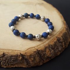 The bracelet is made up of a beautiful collection of dark blue stones, with small black beads placed between them, creating a stunning pattern. The silver-coated lava stone, which serves as a diffuser for any chosen essential oil, allowing you to enjoy its scent for a long time. The combination of the deep blue stones and the silver lava stone creates a magical effect, reminiscent of a starry night sky. Introducing our LavaScent bracelets, featuring stunning lava stones that absorb essential oils for long-lasting fragrance. Enjoy the therapeutic benefits of aromatherapy by adding a few drops of your favorite oil to the porous stone. With a variety of designs to choose from, these bracelets are the perfect accessory for style and wellness. Silver Beaded Bracelets With 8mm Lava Stone Beads, Silver Beaded Bracelet With Lapis Lazuli And Natural Stones, Silver Lava Stone Beaded Bracelets With 8mm Beads, Adjustable Silver Lava Stone Bracelets, Starry Night Bracelet, Elegant Lava Stone Bracelets With Round Beads, Silver Lapis Lazuli Beaded Bracelets For Healing, Elegant Lava Stone Bracelet With Round Beads, Elegant Lava Stone Beaded Bracelets