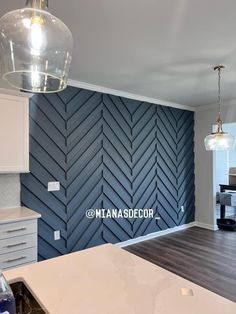 an empty kitchen with wood flooring and blue wallpaper on the back side of the room