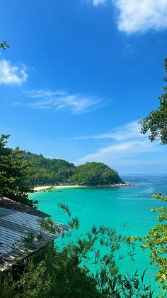 the water is crystal blue and there are trees in front of it on the shore