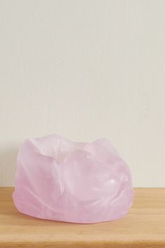 a pink toothbrush holder sitting on top of a wooden table next to a white wall