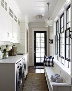 a laundry room with white cabinets and black doors is pictured in this image, along with an entryway that leads to the front door