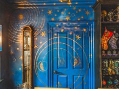 a blue door with stars and moon designs painted on the wall next to a yellow bench