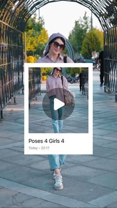 a woman is walking down the sidewalk in front of a metal structure with a video screen