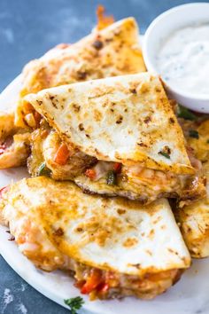 several quesadillas stacked on a plate with dipping sauce