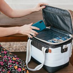 a woman is sitting on a bench and looking at her phone while holding an open suitcase