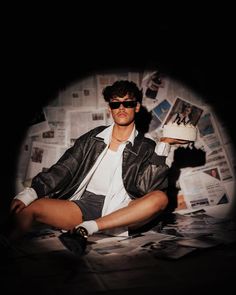 a man sitting on the floor with a cake in his hand and newspaper behind him