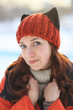 a woman wearing an orange hat with black cat ears