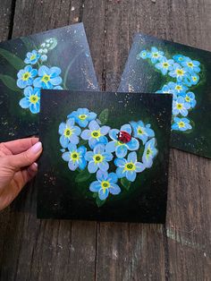 three cards with blue flowers and a ladybug on them are being held up