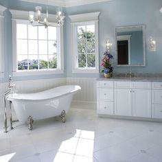 a bathroom with blue walls and white fixtures, including a claw foot tub in the center