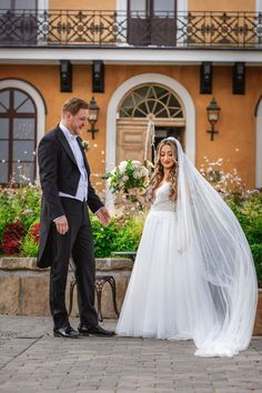 a bride and groom standing in front of a building