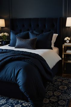 a bed with blue sheets and pillows in a bedroom next to two nightstands on either side of the bed