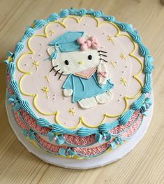 a hello kitty birthday cake with blue icing and pink frosting, on top of a wooden table