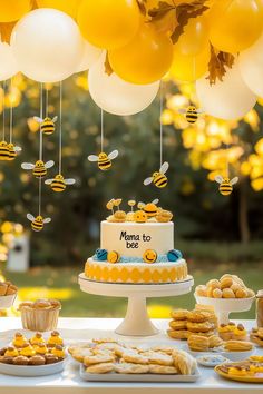 a table topped with cake and desserts covered in honeycombs next to balloons