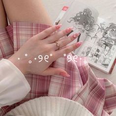 a woman with pink nails is sitting on a bed