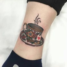 a tattoo on the ankle of a woman with a coffee cup and flowers in it