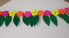 some paper flowers and leaves on a white surface