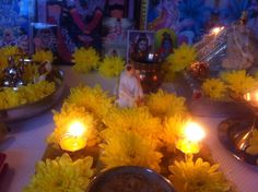 candles and flowers on a table with pictures in the backgroufground, surrounded by other decorations