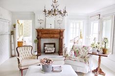 a living room filled with furniture and a chandelier hanging from the ceiling over a fire place