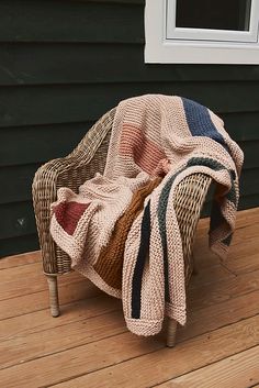 a chair with a blanket on top of it sitting on a wooden floor next to a window