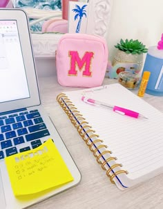 a laptop computer sitting on top of a desk next to a notepad and pen