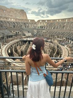 a woman in a white dress looking at the inside of an ancient roman colossion