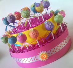 there is a cake with many candies on it in the pink box and flowers