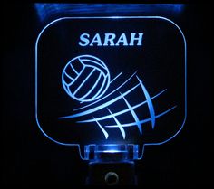 an illuminated sign with the word sarah and a volleyball ball on it's side