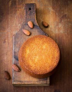 a cake sitting on top of a wooden cutting board next to almonds and a knife