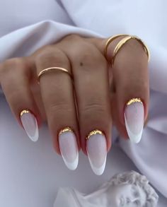 a woman's hand with white and gold nail polishes on her nails, holding two rings