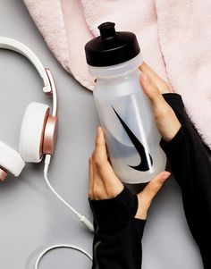 a person is holding a water bottle and headphones