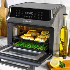 an open oven with food cooking in it next to some lemons and wine bottles