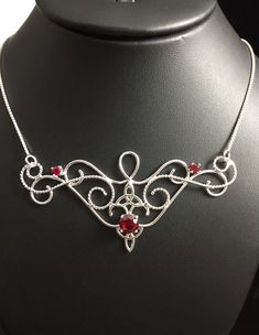 I love Victorian themed jewelry with an Edwardian, Elvish-inspired flair, and I hope I've captured it within this piece! I shall custom create this gorgeous Renaissance style necklace, in sterling silver, with three lab faceted Garnet gemstones. The center gemstone is 8mm round and the two sides are 4mm round. The chain will be soldered to each side and I will use a 1.2mm thick sterling box chain. I think this piece looks best near the collarbone area, so please measure the circumference of your Fantasy Style Silver Jewelry With Unique Design, Red Artisan Jewelry For Wedding, Artisan Red Jewelry For Wedding, Red Handmade Jewelry For Wedding, Handmade Silver Fantasy Jewelry, Handmade Silver Fantasy Necklace, Handmade Fantasy Silver Jewelry, Hand Forged Fantasy Jewelry As A Gift, Artisan Wire Wrapped Jewelry For Wedding