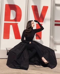 a woman sitting on the ground in a black dress