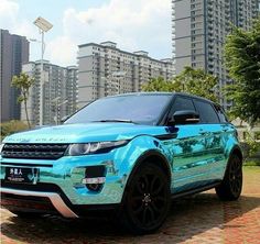 a blue range rover parked in front of some tall buildings