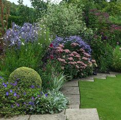 a garden with lots of different types of flowers and plants in it's borders