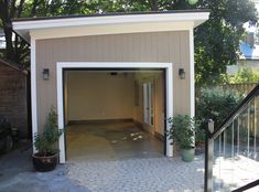 an open garage door on the side of a house with potted plants in it