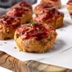 mini meatloafs with ketchup are sitting on a cutting board