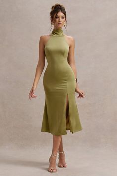 a woman wearing a green dress with high slits on the side and an asymmetrical neckline