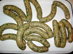 several sausages are arranged on a white platter with green sprinkles