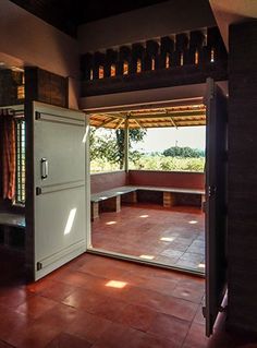 an open door leading into a room with red tile flooring and wooden ceiling beams