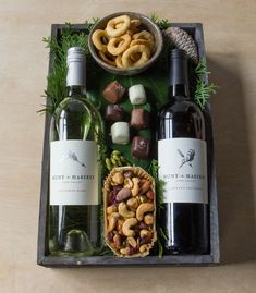 two bottles of wine and some snacks on a tray