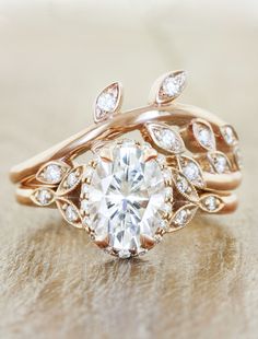 a close up of a ring with a diamond in the center and leaves on it