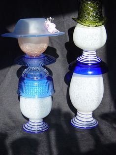 two blue and white vases are sitting side by side on a black surface with a hat on top