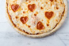 a pizza with heart shaped toppings on it sitting on top of a marble counter