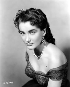 an old black and white photo of a woman in a dress with pearls on her head