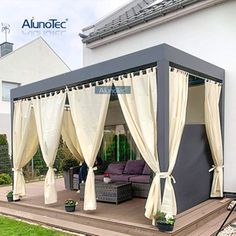 an outdoor living area with curtains on the side and couches in the back ground