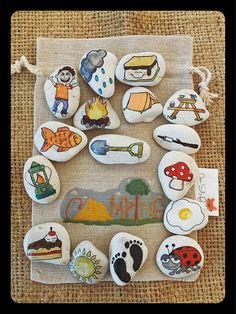 some rocks with different pictures on them sitting on a cloth covered bag, next to a drawstring