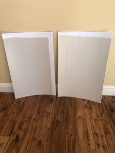 two pieces of white paper sitting on top of a wooden floor next to each other